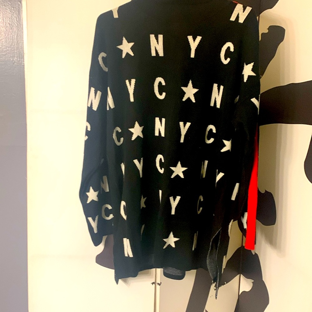 Black sweater with white letters and red trim down each sleeve